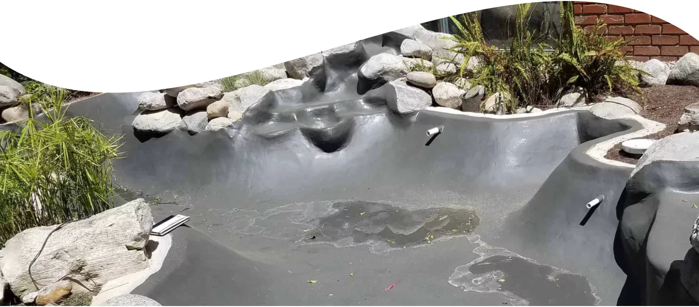 Finished polyurea aquatic coatings membrane over a freeform pond shell and rock waterfall